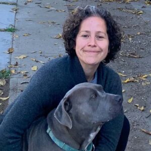 Allison Cardona hugging her pit bull dog on a sidewalk